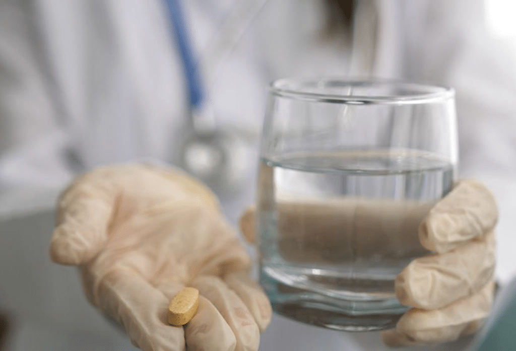 Senior holds out a glass of water with a pill of elmiron, zofran, paragard, or valsartan